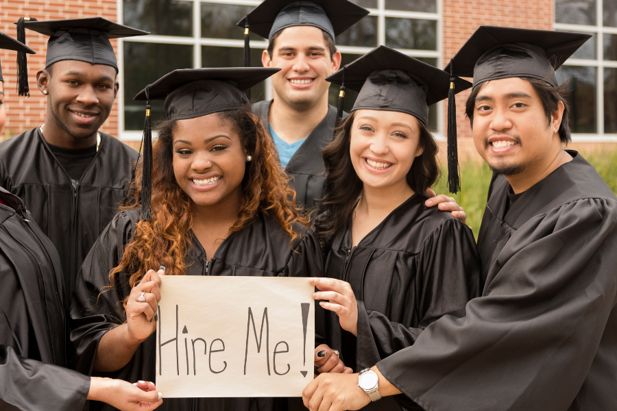 Photo of grads holding hire me sign