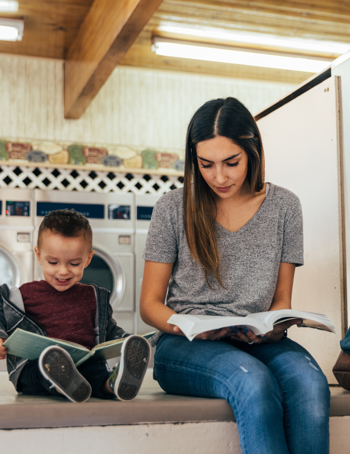 Student mother studying with young son at laundromat