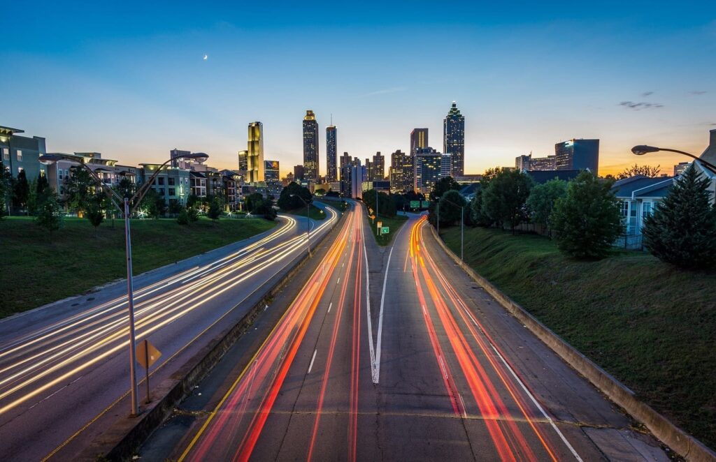 Time-lapsed photo of highway traffic heading to and from the city skyline