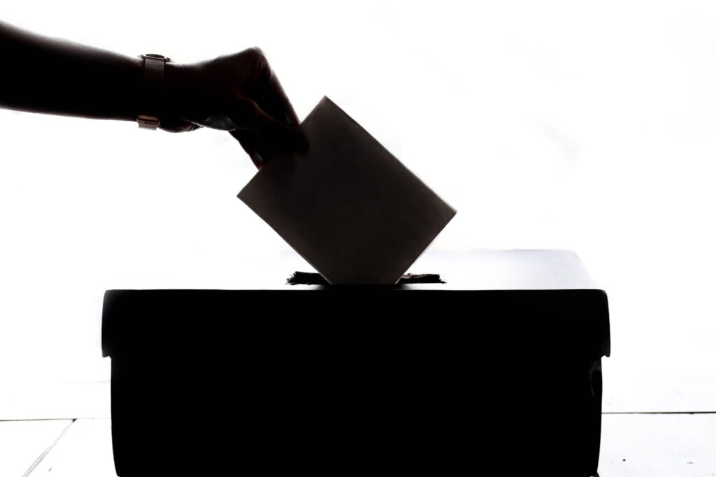 silhouette of hand place a ballot in box