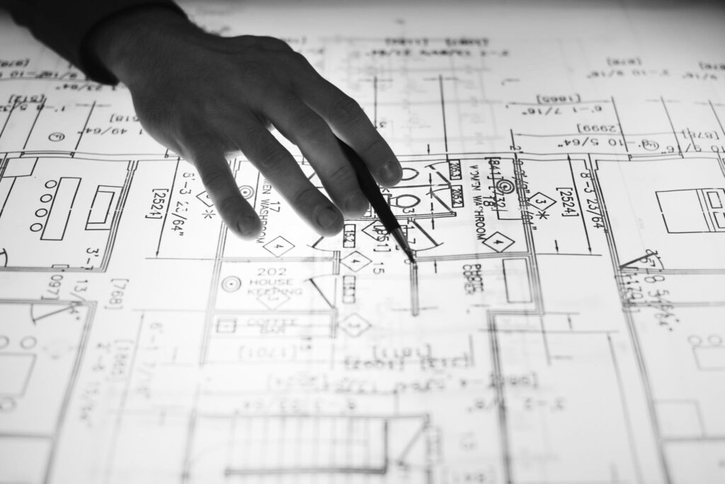 Hand holding pen above a blueprint layout